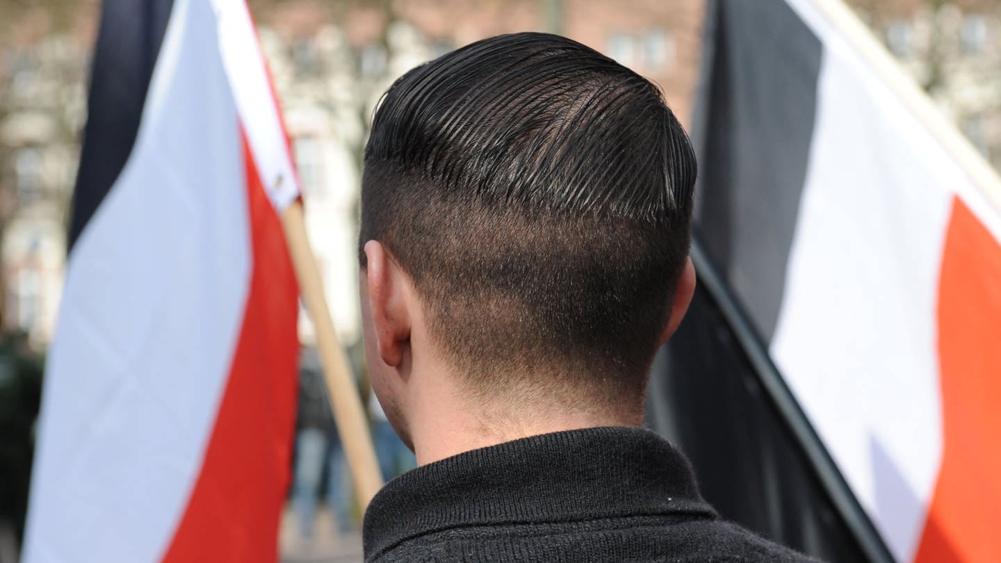 Ein Mann steht mit einer Nazi-Flagge bei einer Kundgebung. (Foto: Dzendziol)