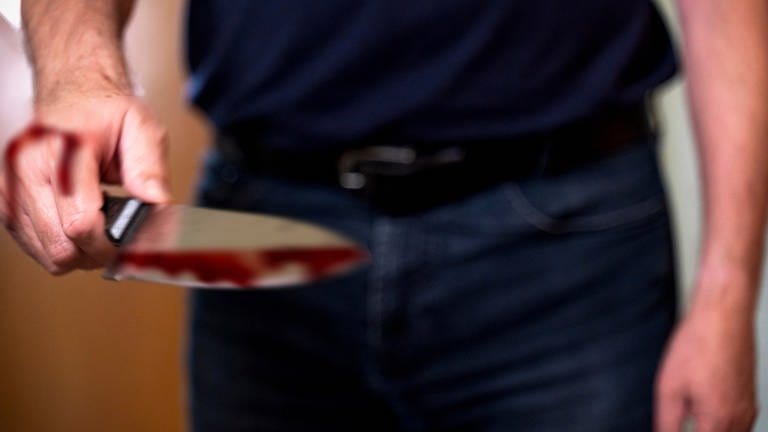 Symbolbild: Ein Mann hat ein Messer in Hand, das mit Blut verschmiert ist (picture allianceMichael Bihlmayer).