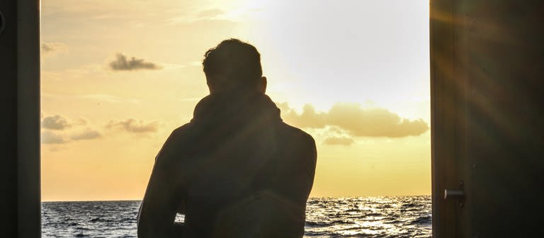 Ein junger Flüchtling von hinten auf einem Boot auf dem Mittelmeer (Foto: picture-alliance / Reportdienste, Picture Alliance)