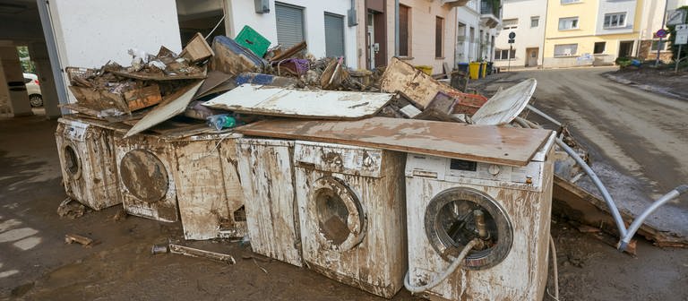 Verschlammte Waschmaschinen und zerstörte Möbel stehen im Ahrtal auf der Straße (Foto: SWR)