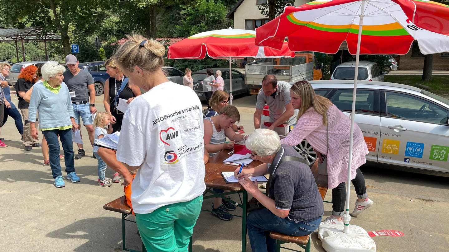 Arbeiterwohlfahrt hat in Ahrbrück einen Stand aufgebaut, an dem Betroffene der Hochwasserkatastrophe im Ahrtal an einem Tisch Anträge auf Soforthilfe ausfüllen (Foto: SWR)