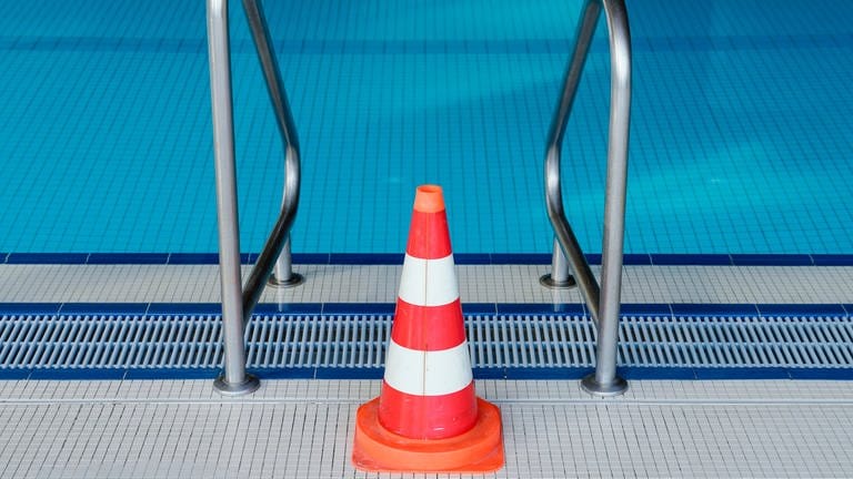 Eine Pylone steht in einem Hallenbad an einer Leiter des Schwimmerbeckens. Das Schwimmbad ist wegen der Coronakrise bis auf weiteres geschlossen.  (Foto: picture-alliance / Reportdienste, Picture Alliance)