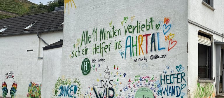 Auf einer Hauswand in Dernau steht der Spruch: "Alle elf Minuten verliebt sich ein Helfer ins Ahrtal".  (Foto: SWR)