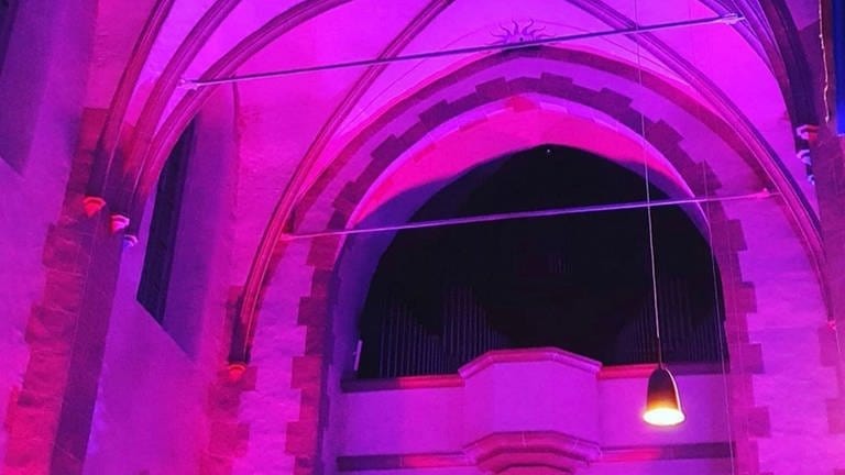 Der Altarraum der St. Martinskirche in Oberwesel erstrahlt bei der Lichtkunstaktion Rheinleuchten in lila. (Foto: Pressestelle, Tourist-Information Oberwesel )