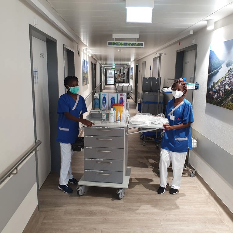 Zwei Pflegerinnen aus Namibia stehen im Klinikflur mit Wagen (Foto: SWR)
