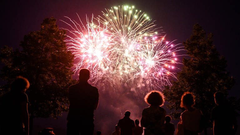 Feuerwerk am Himmel mit Menschen im Vordergrund (Foto: picture-alliance / Reportdienste, picture alliance/dpa/KEYSTONE | Jean-Christophe Bott)