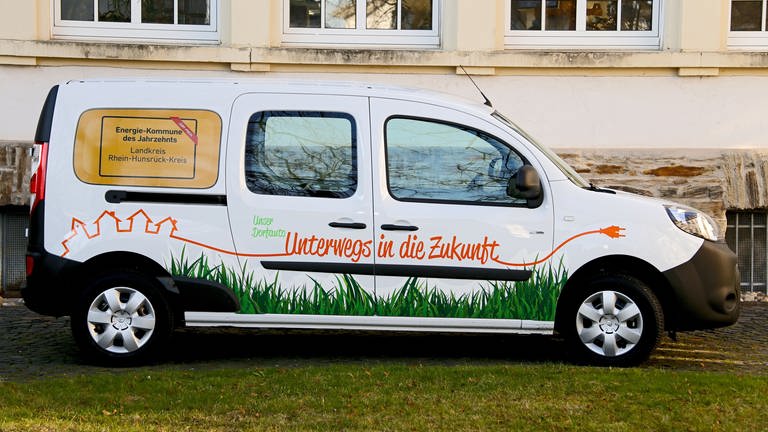 ein weißer Kleinwagen mit der Aufschrift "unser Dorfauto" Im Rhein-Hunsrück-Kreis werden drei Jahre lang solche E-Dorfautos getestet.  (Foto: Rhein-Hunsrück-Kreis/Pressestelle)