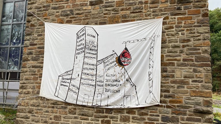 Banner an der St Andreas Kirche in Ahrbrück verdeutlicht Kritik an Abriss (Foto: SWR)