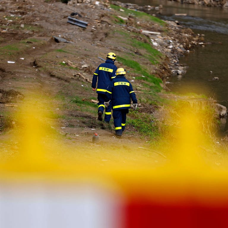Zwei Rettungskräfte laufen an der zerstörten Ahr nach der Flutkatastrophe entlang (Foto: IMAGO, Christoph Hardt)