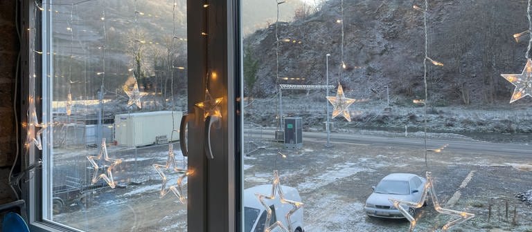 Beleuchtete Weihnachtssterne hängen in einem Fenster, aus dem man auf das winterliche Ahrtal blickt  (Foto: SWR)