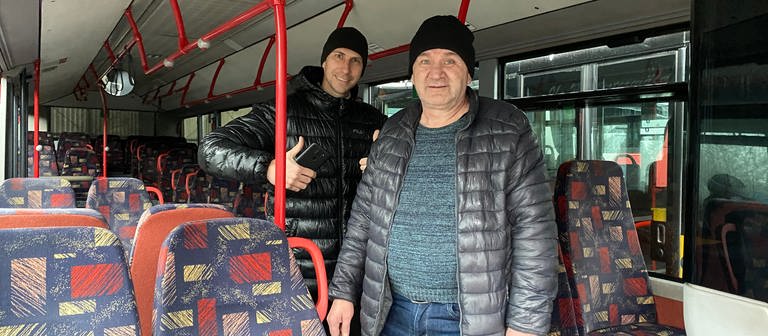 Zwei Männer stehen in einem Linienbus und blicken erfreut in die Kamera. (Foto: SWR)
