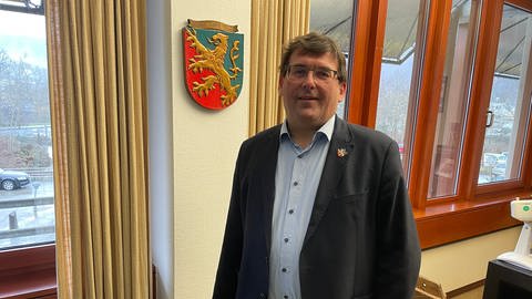 Jörg Denninghoff, Landrat des Rhein-Lahn-Kreises, steht vor einem Wappen in seinem Büro (Foto: SWR)