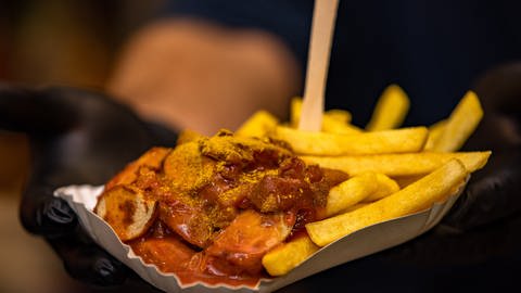 Eine Hand hält eine Pappschachtel mit Currywurst und Fritten (Foto: picture-alliance / Reportdienste, Picture Alliance)