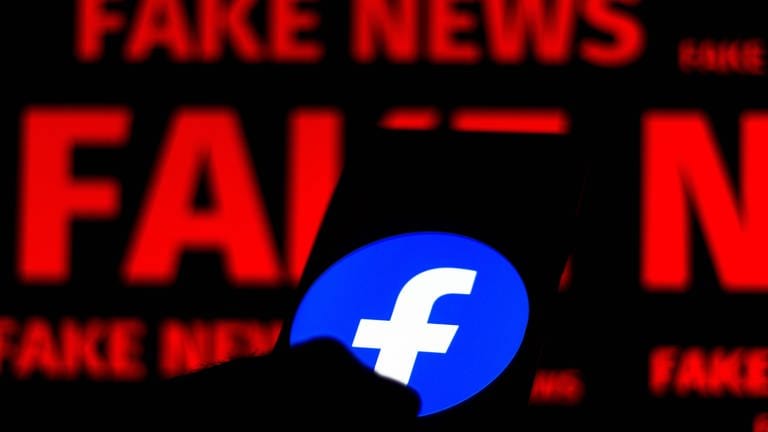 Smartphone mit Facebook-Logo und der Schrift "Fake News" im Hintergrund (Foto: IMAGO, ZUMA Wire)