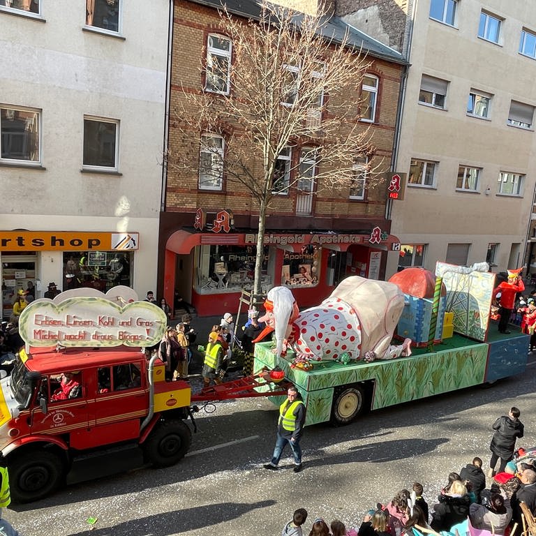 Ein Motivwagen beim Koblenzer Rosenmontagszug 2023: Ein deutscher Michel, dazu ein Schild mit der Aufschrift "Erbsen, Linsen, Kohl und Gras - Michel macht darauf Biosgas!" (Foto: SWR)