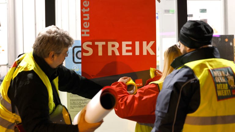 Streikende kleben ein Plakat mit der Aufschrift "Heute Streik" an eine Scheibe. Airport-Mitarbeiter der Luftsicherheit des Flughafens KölnBonn streiken  für bessere Löhne. (Foto: dpa Bildfunk, Picture Alliance)