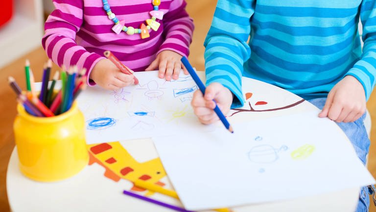Zwei Kinder malen an einem kleinen Tisch. (Foto: IMAGO, stock&people)