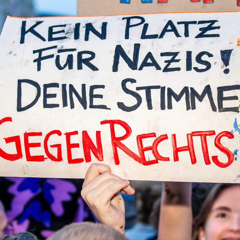 Auf einer Demo wird ein Plakat mit der Aufschrift: "Kein Platz für Nazis! Deine Stimme gegen Rechts" hochgehalten. (Foto: dpa Bildfunk, Picture Alliance)