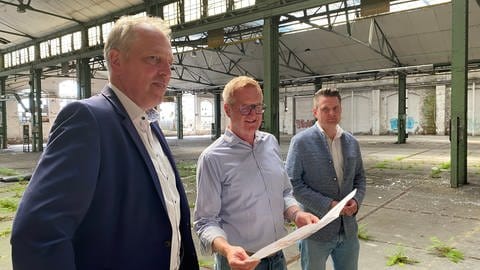 Investor Peter Merz (Mitte) zeigt Betzdorfs Bürgermeister Geldsetzer (li) und Wirtschaftsförderer Michael Becher seine Pläne für das EAW-Areal. (Foto: SWR)