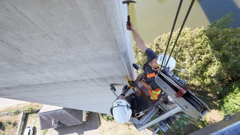 Brückeninspektoren an einem sehr hohen Brückenpfieler sind mit einem Hammer am Beton unterwegs (Foto: dpa Bildfunk, picture alliance/dpa | Thomas Frey)