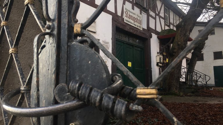 Blick durch ein Tor: Der Eingang zum alten Hotel Königstuhl in Rhens ist mit einem Vorhängeschloss verschlossen. (Foto: SWR)