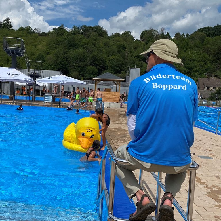 Eine Badeaufsicht sitzt auf einem Stuhl und beobachtet das Treiben im Schwimmbecken. Auf dem Rücken des Shirts steht: "Freibadteam Boppard" (Foto: SWR)