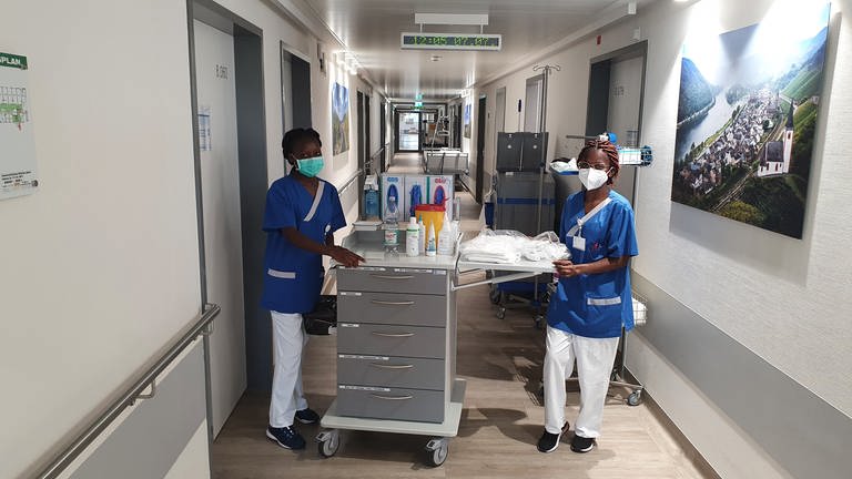 Zwei Pflegerinnen aus Namibia stehen im Klinikflur mit Wagen