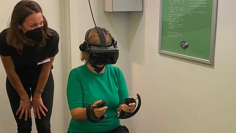 Klimaschutzministerin Katrin Eder testet das neue Virtual-Reality-Spiel im Mosellum in Koblenz. (Foto: SWR)