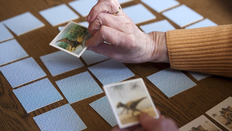 Eine Seniorin spielt am in einer Wohnung ein Memory (Foto: picture-alliance / Reportdienste, picture alliance / dpa Themendienst | Silvia Marks)