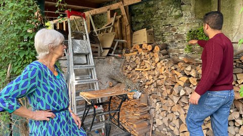 Wohnen für Hilfe in Koblenz: Gerda Pfandzelter und Moaath Saada stehen vor einer Wand voller Holzscheite (Foto: SWR)