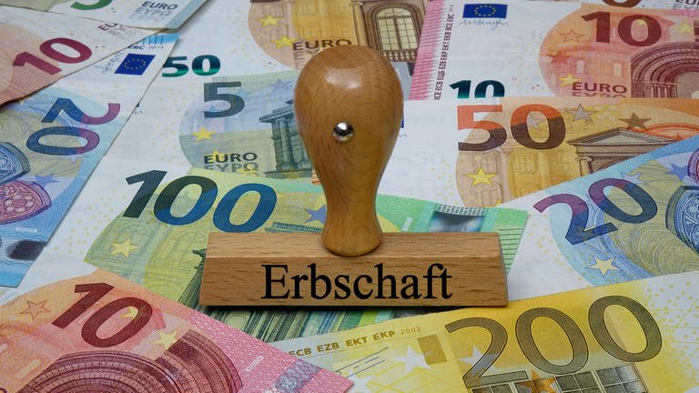 Zahlreiche Euro-Geldscheine und ein Stempel mit dem Aufdruck "Erbschaft" (Foto: IMAGO, IMAGO / Steinach)