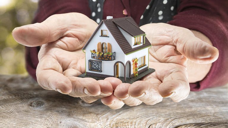 Ein Mann hält ein Haus in der Hand, das vererbt wird (Foto: SWR)