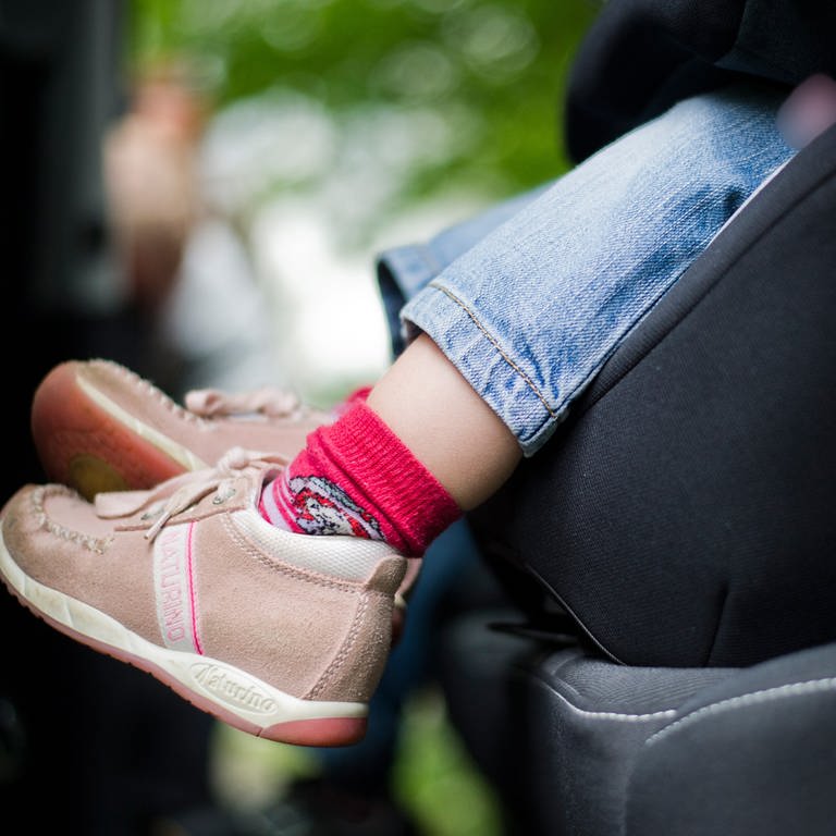 Ein Kleinkind mit braunen Schuhen und roten Socken sitzt im Autositz. Man sieht den Fußbereich und den unteren Teil des Sitzes. (Foto: picture-alliance / Reportdienste, Nicolas Armer)