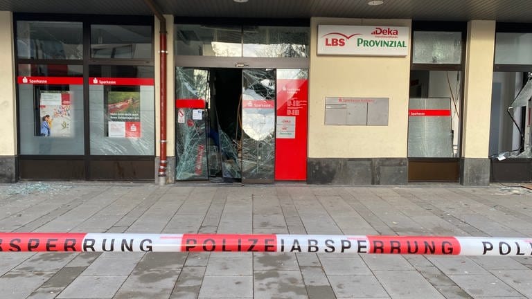 Eine zerstörte Glastür bei einer Sparkasse in Koblenz und eine Absperrung durch die Polizei