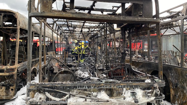 Mehrere Feuerwehrmänner löschen die letzten Brände in einem abgebrannten Bus. Die Feuerwehr schätzt den Sachschaden auf knapp eine Million Euro. (Foto: SWR)