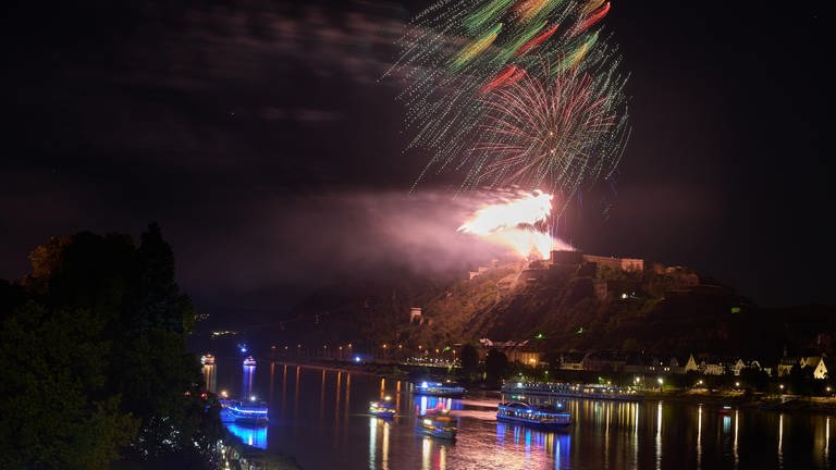 Ein Feuerwerk über der Festung Ehrenbreitstein, im Vordergrund festliche Schiffe auf dem Rhein