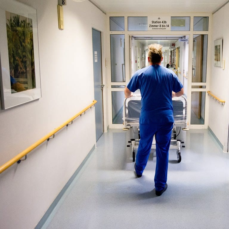 Krankenpfleger schiebt leeres Bett in Klinik