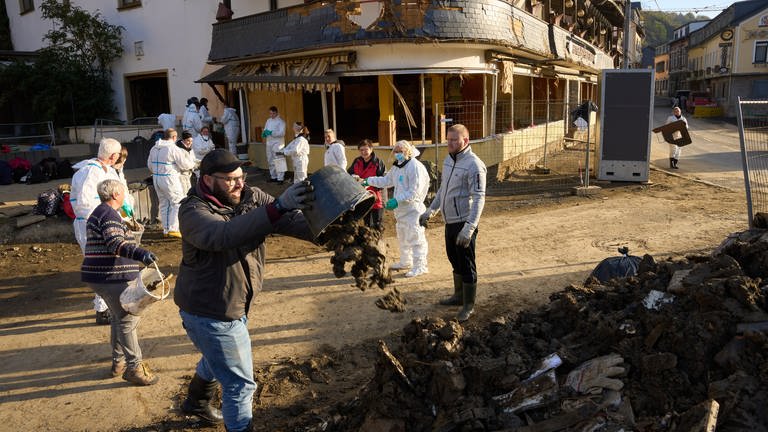 Helfer befördern Schlamm aus einem Haus in Altenahr im Ahrtal nach der Flutkatastrophe 