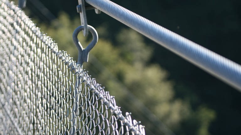 Nahaufnahme eines Gittergeländers aus Metall an einer Hängeseilbrücke (Foto: IMAGO, IMAGO / Eibner)