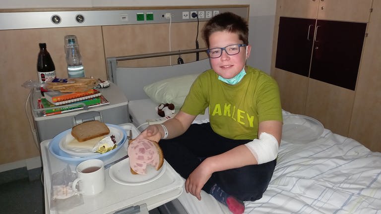 Der 12-jährige Jakob sitzt auf seinem Krankenbett und schaut in die Kamera (Foto: SWR)