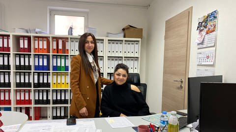 Zwei Frauen stehen in einem Büro hinter einem Schreibtisch. Gülten Kumas (rechts), Geschäftsführerin der Spedition Telci in Mogendorf im Westerwald und Hümeyra Türk, Tochter des Inhabers, organisieren die Hilfstransporte in die Türkei.