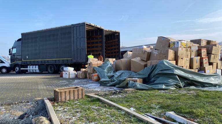 Ein Lkw steht auf einem Parkplatz, davor viele Kartons. Nach dem Erdbeben in der Türkei fährt die Speditionsfirma Telci aus Mogendorf im Westerwald Spenden an die Grenze.
