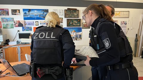 Beamte des Hauptzollamts Koblenz lassen sich im Büro Dokumente zeigen, Kontrolle Mindestlohn 09.03.2023 (Foto: SWR)