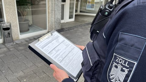 Beamter des Hauptzollamts Koblenz mit Fragebogen in der Hand, 08.03.2023 (Foto: SWR)