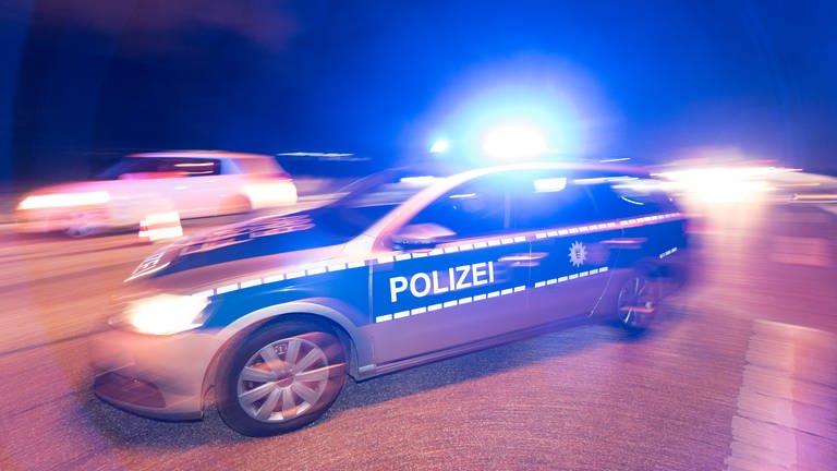 Polizeiauto mit Blaulicht verbeifahrendes Auto unscharf