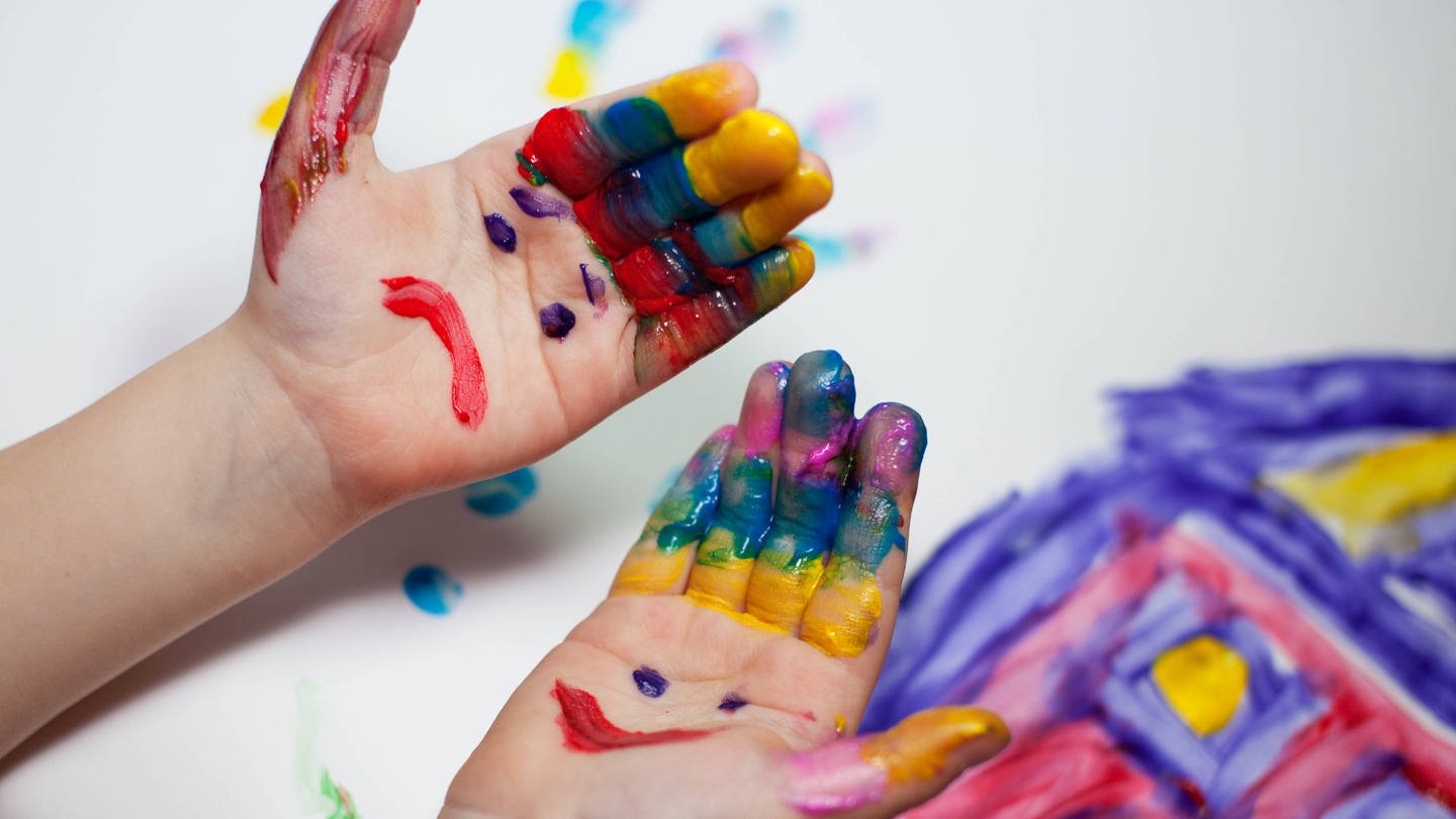 Bunte bemalte Kinderhände mit Gesichtern auf der Handinnenfläche (Foto: IMAGO, Nailia Schwarz)
