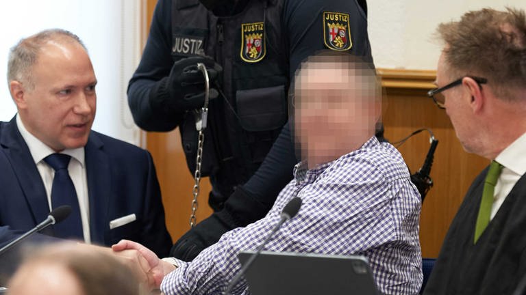 Einer der Angeklagten im Prozess gegen die sogenannten Vereinten Patrioten sitzt mit seinen Verteidigern auf der Anklagebank im Oberlandesgerich Koblenz