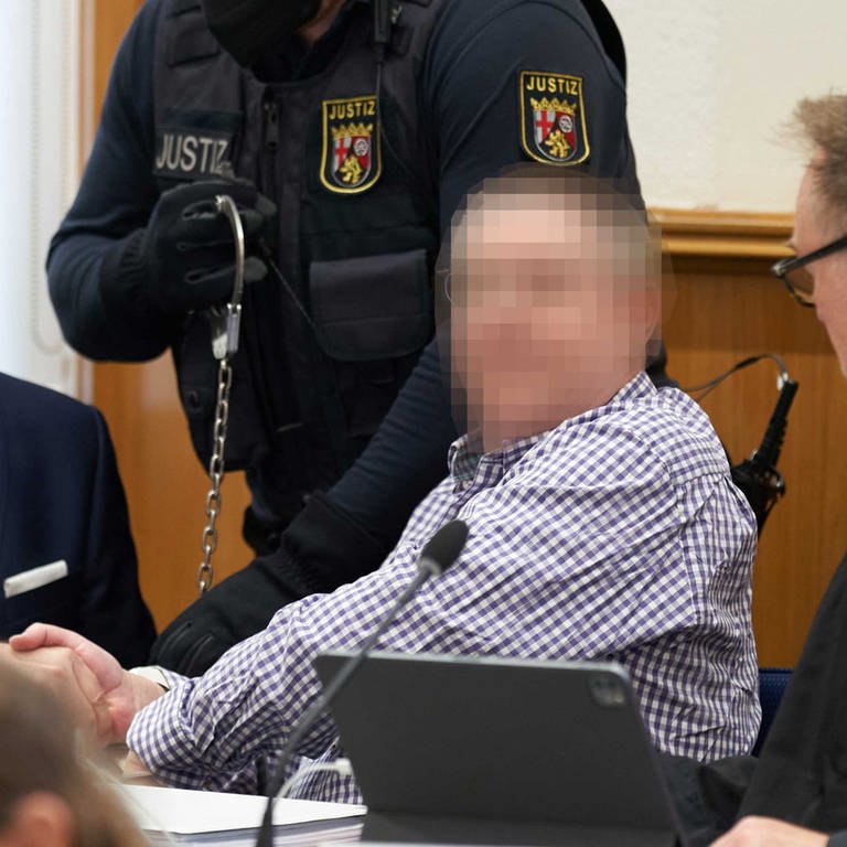 Einer der Angeklagten im Prozess gegen die sogenannten Vereinten Patrioten sitzt mit seinen Verteidigern auf der Anklagebank im Oberlandesgerich Koblenz
