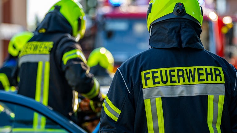 Mehrere Feuerwehrleute von hinten, auf dem Rücken der Uniform steht "Feuerwehr": Feuerwehrleute haben in Neitersen im Kreis Altenkirchen einen Mann von einem Hausdach gerettet.  (Foto: picture-alliance / Reportdienste, Picture Alliance)