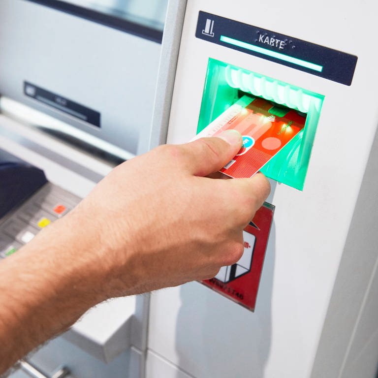Eine Hand schiebt eine Karte in einen Geldautomaten: Die Sparkasse Koblenz nimmt nachts wieder fünf Geldautomaten in Betrieb